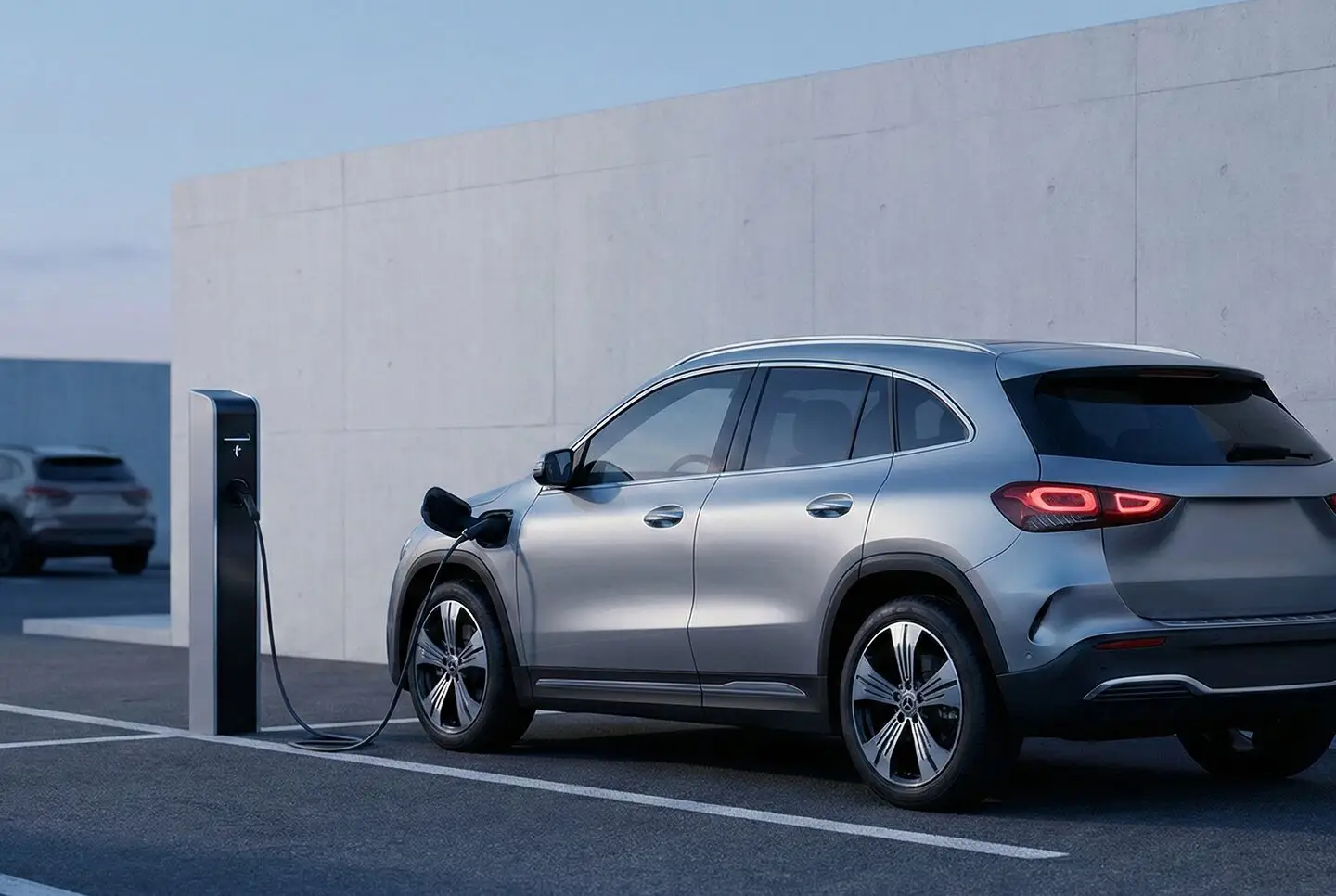 Silbernes Elektroauto lädt an einer Ladesäule auf einem Parkplatz